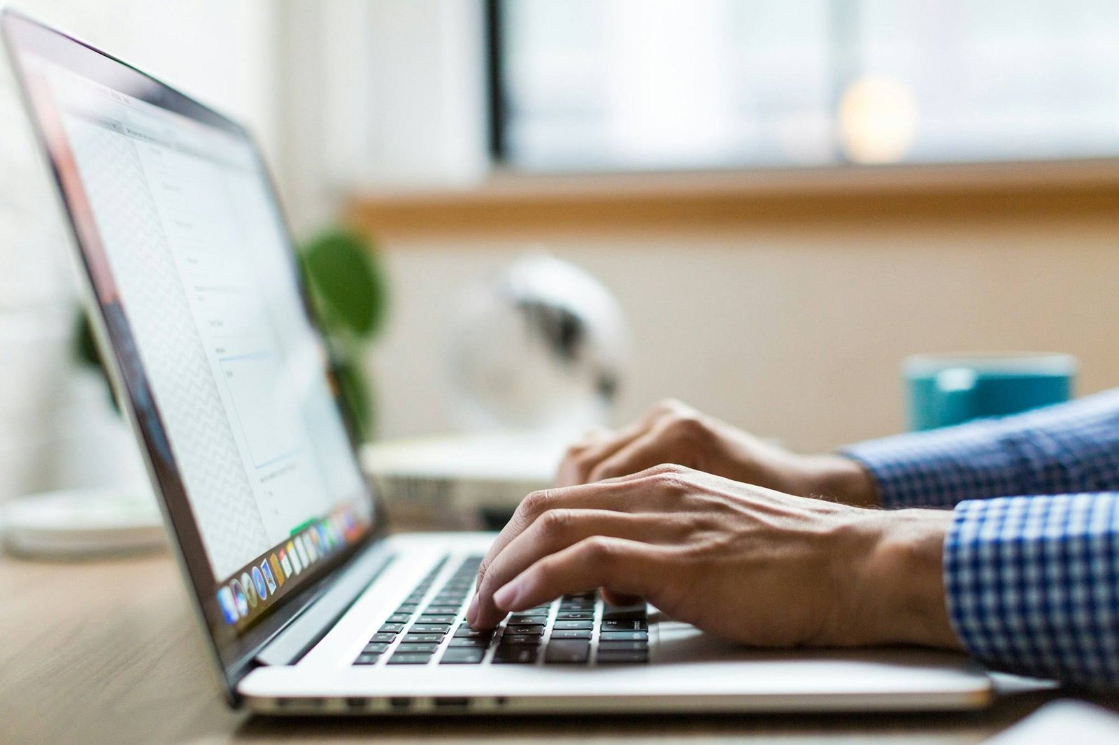 Person typing on a laptop at a bright desk
