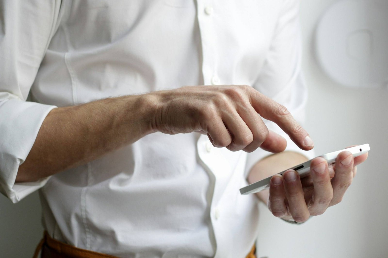 Person in a white shirt dialling a number on a smartphone